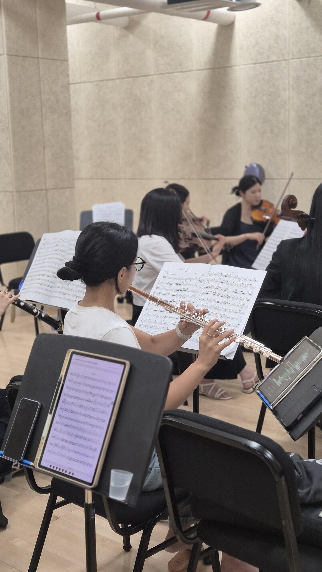 플루트를 연주하는 단원과 뒤편의 현악 파트